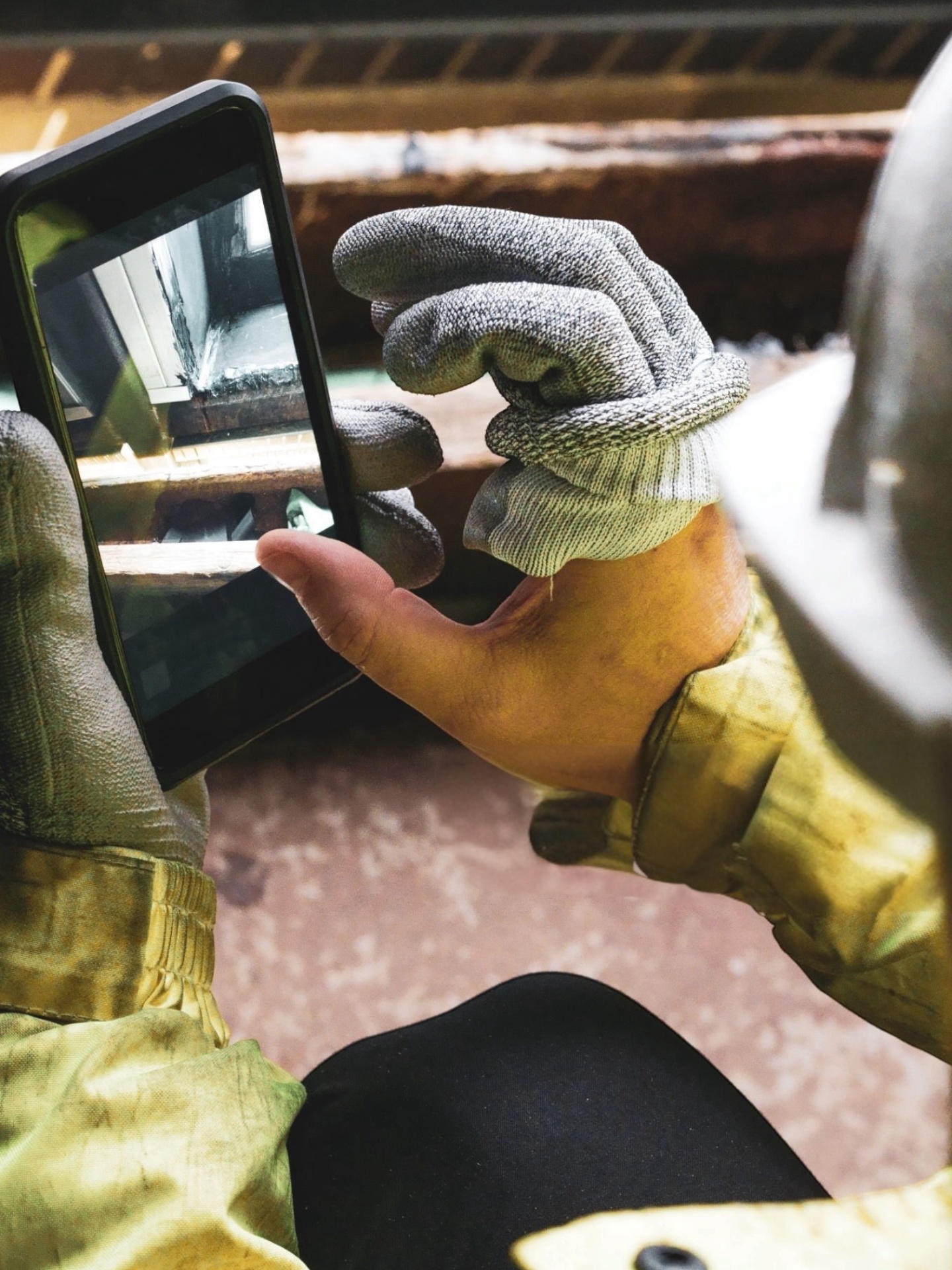 Contractor in work gloves photographing a job site with a phone