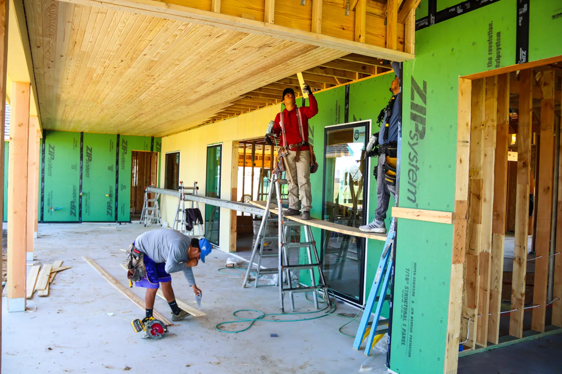 Crew installing trim and framing on a covered patio of a new home build